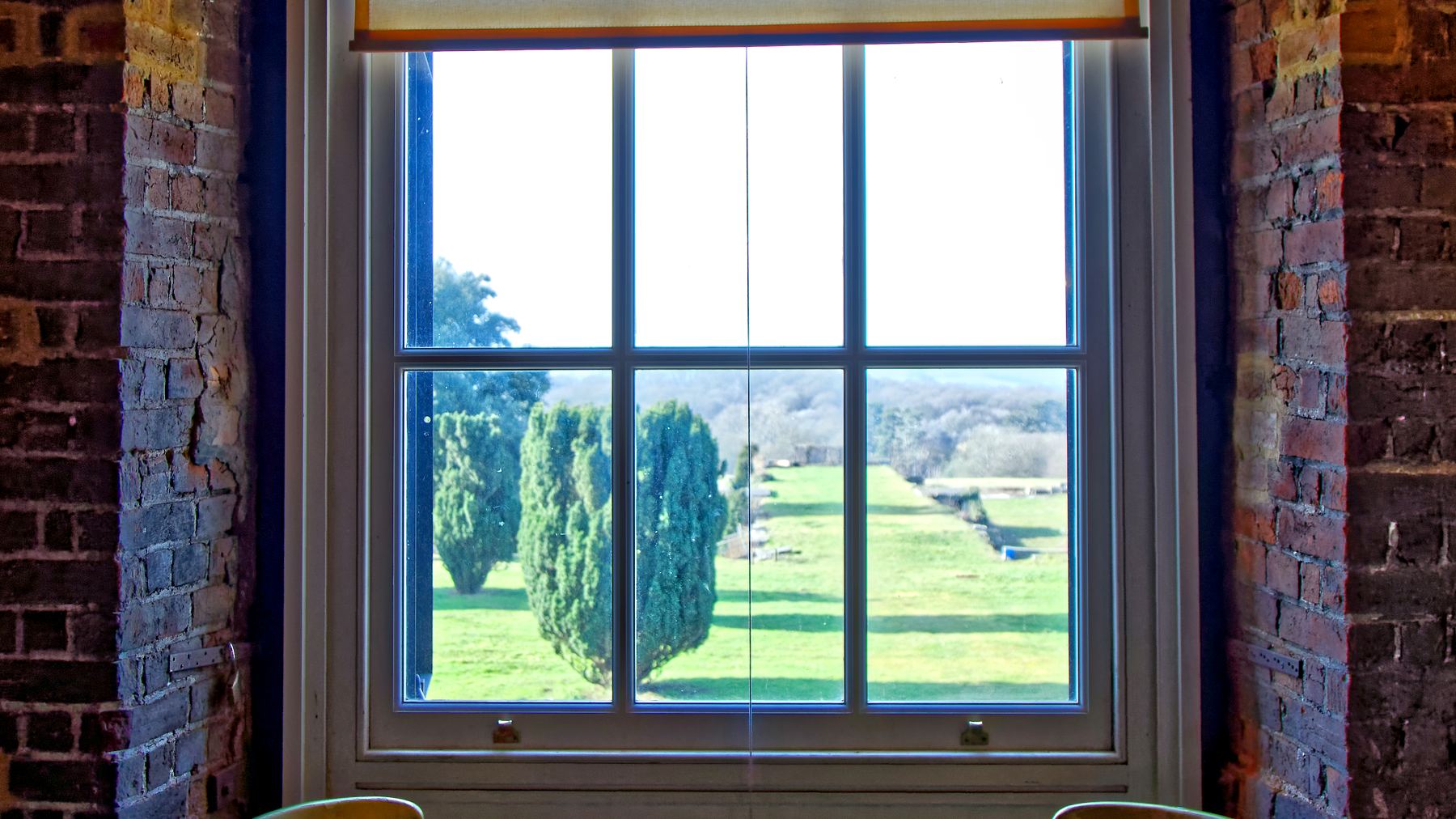 Two chairs beneath a tall sash window, looking out onto parkland.