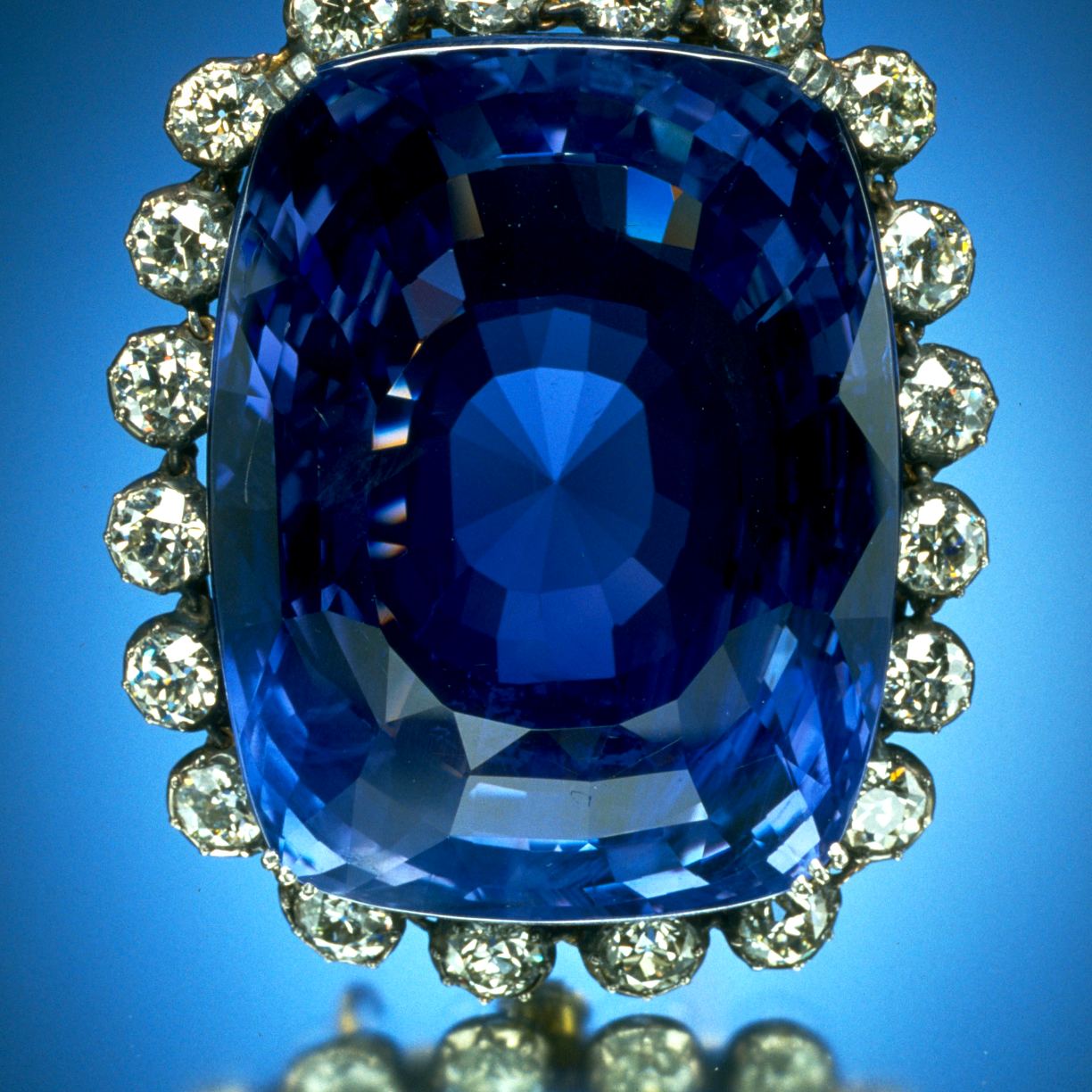 A large cushion-cut blue sapphire ringed with diamonds.