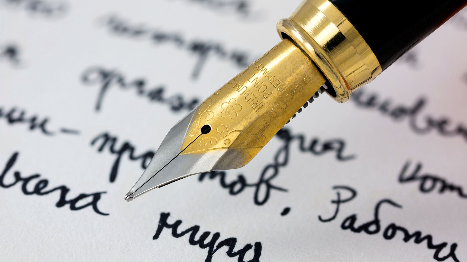 A gold fountain pen nib resting on a handwritten letter.